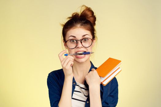 woman student with glasses notepad with pen yellow background. High quality photo