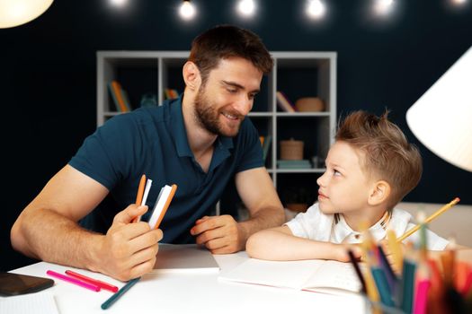 Father helping his little son with school homework close up