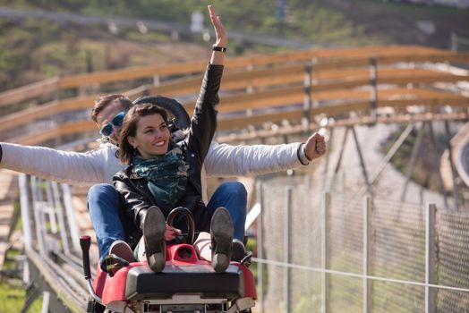 Excited young couple enjoys driving on alpine coaster