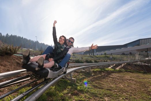 Excited young couple enjoys driving on alpine coaster