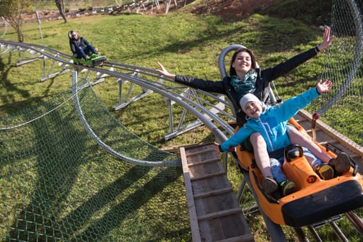 young excited mother and son enjoys driving on alpine coaster