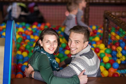 happy family enjoying free time young parents and kids playing in the pool with colorful balls at childrens playroom