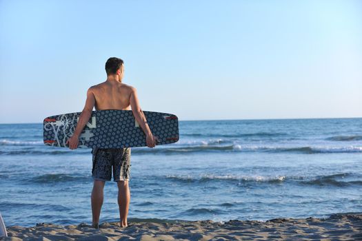 Portrait of a strong young  surf  man at beach on sunset in a contemplative mood with a surfboard