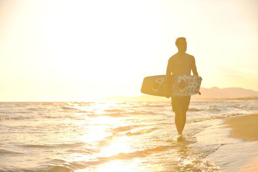 Portrait of a strong young  surf  man at beach on sunset in a contemplative mood with a surfboard