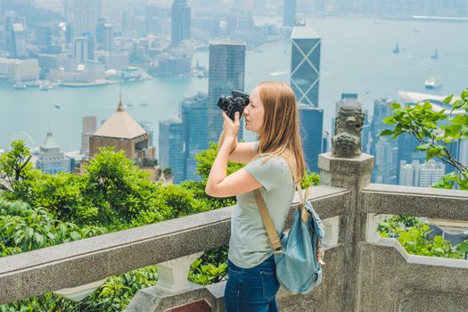 Young woman taking photos of victoria harbor in Hong Kong, China.