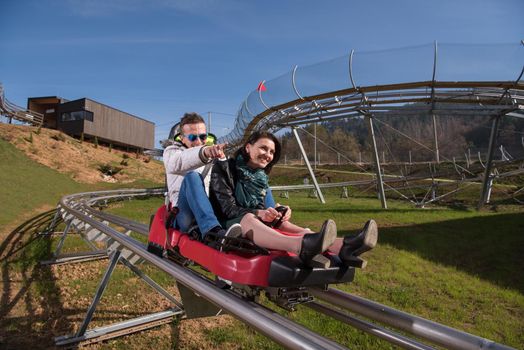 Excited young couple enjoys driving on alpine coaster