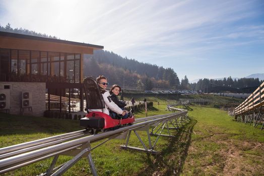 Excited young couple enjoys driving on alpine coaster