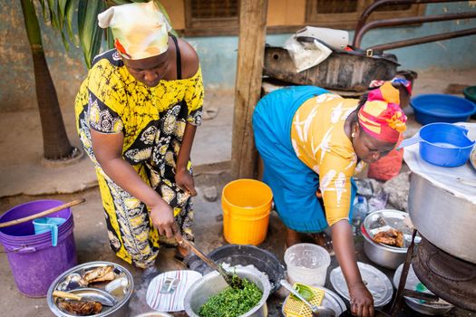 African woman cooking traditional food at street