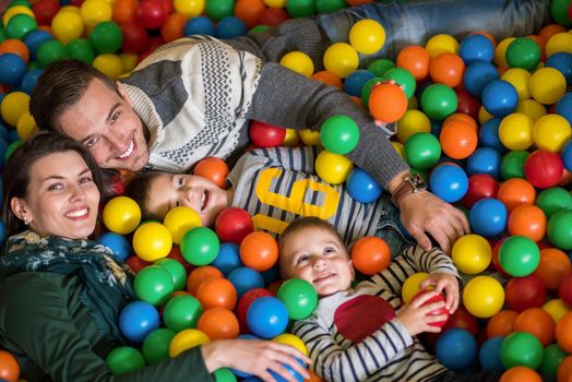 happy family enjoying free time young parents and kids playing in the pool with colorful balls at childrens playroom