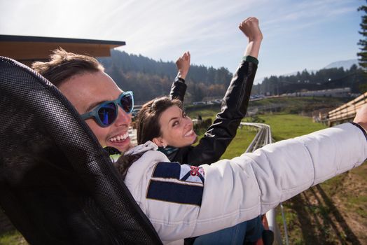 Excited young couple enjoys driving on alpine coaster