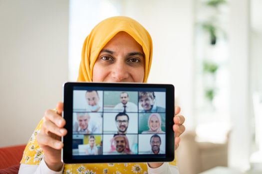 Muslim womah holding tablet with zoom conference screen