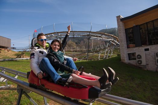 Excited young couple enjoys driving on alpine coaster