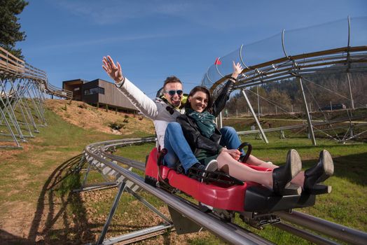 Excited young couple enjoys driving on alpine coaster