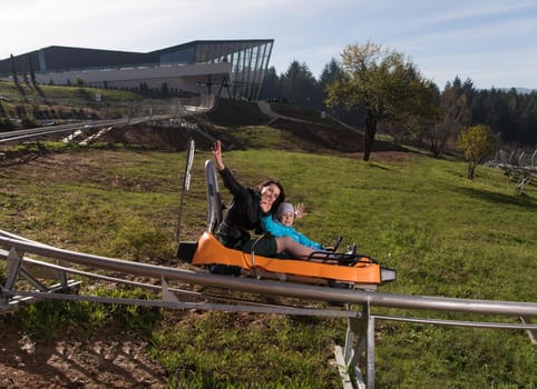 young excited mother and son enjoys driving on alpine coaster