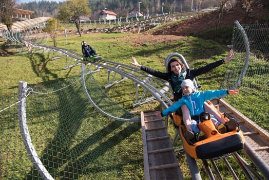 young excited mother and son enjoys driving on alpine coaster