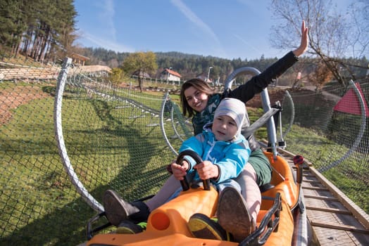 young excited mother and son enjoys driving on alpine coaster