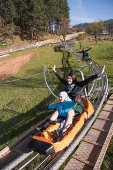 young excited mother and son enjoys driving on alpine coaster