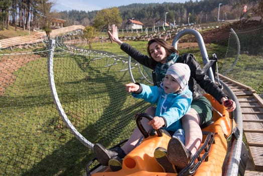 young excited mother and son enjoys driving on alpine coaster