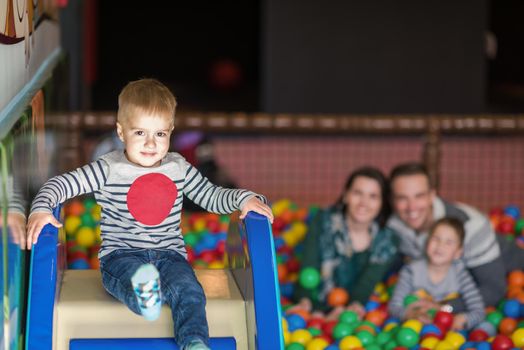 happy family enjoying free time young parents and kids playing in the pool with colorful balls at childrens playroom