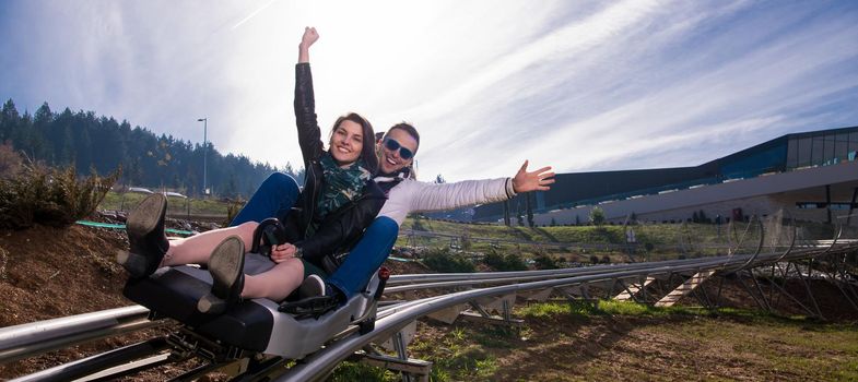 Excited young couple driving alpine coaster while enjoying beautiful sunny day in the nature