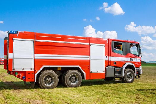 Fire truck on a field under a blue sky. Rescuers.