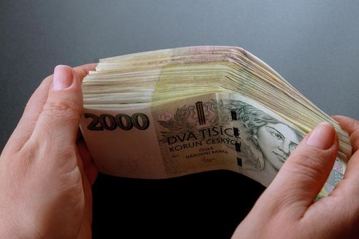 Bundle of Czech money in the hands of a woman on a black background. Banknotes of 2000.