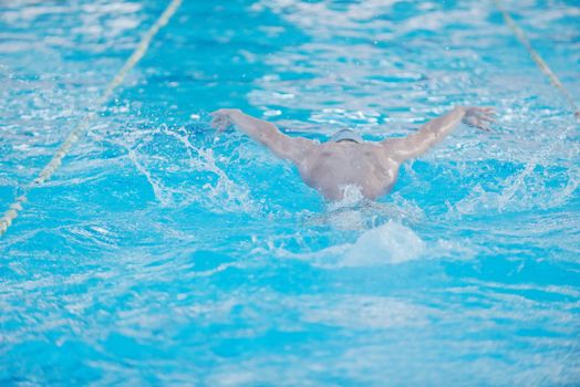 Happy muscular swimming woman  wearing glasses and cap at swim pool and represent health and fit concept