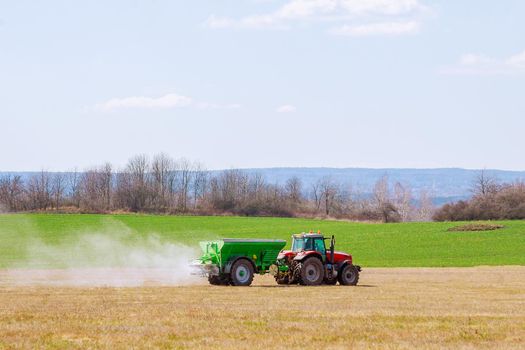 Agricultural work. Tractor spreading fertilizer on grass field.