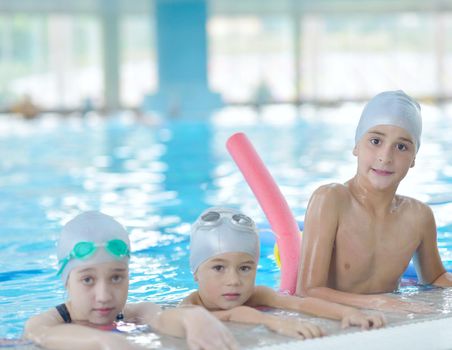 group of happy kids children   at swimming pool class  learning to swim