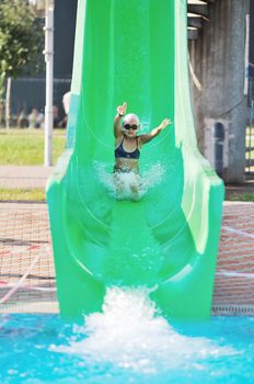 happy girl have fun  on water slide at outdoor swimming pool