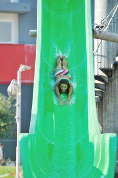 happy girl have fun  on water slide at outdoor swimming pool