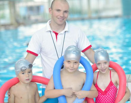 group of happy kids children   at swimming pool class  learning to swim