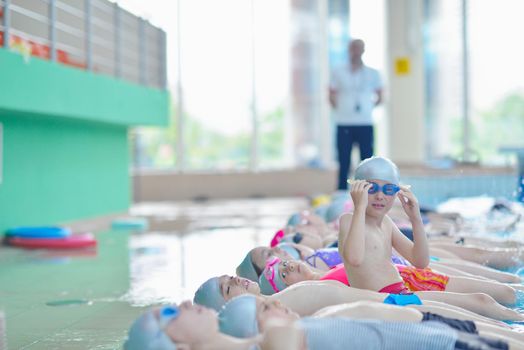 group of happy kids children   at swimming pool class  learning to swim