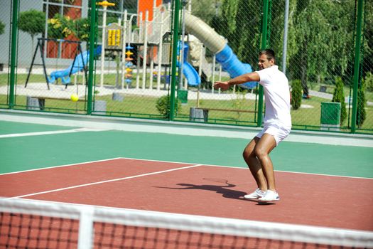 young man play tennis outdoor on orange tennis court at early morning