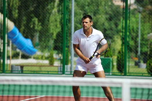 young man play tennis outdoor on orange tennis court at early morning