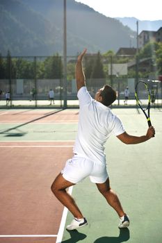 young man play tennis outdoor on orange tennis field at early morning