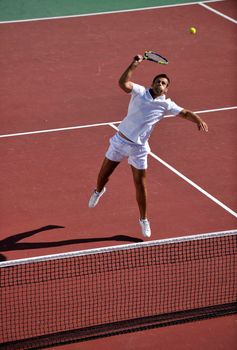 young man play tennis outdoor on orange tennis field at early morning