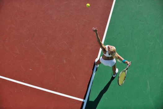 young fit woman play tennis outdoor on orange tennis field at early morning