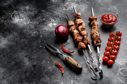 Shish kebab BBQ meat with onions and tomatoes set, on black dark stone table background, with copy space for text