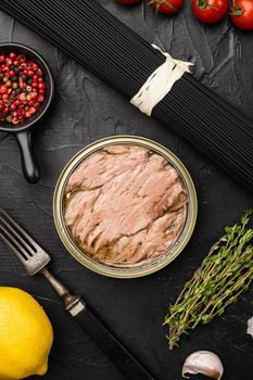 Open tuna tin set, on black dark stone table background, top view flat lay