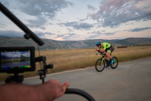 triathlon athlete riding professional racing bike on morning workout sunset or sunrise in background