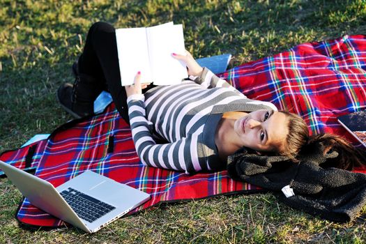 young teen girl read book and study homework outdoor in nature with blue sky in background