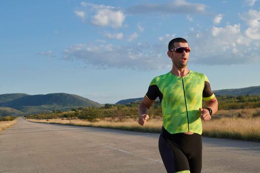 triathlon athlete running  on morning training sunrise in the background