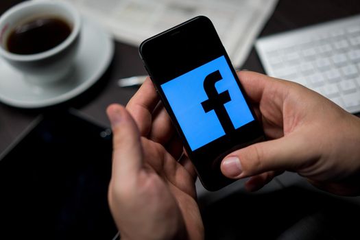 New York, New York / USA - 11 11 2019: Logo of Facebook on the iPhone X in hands in office