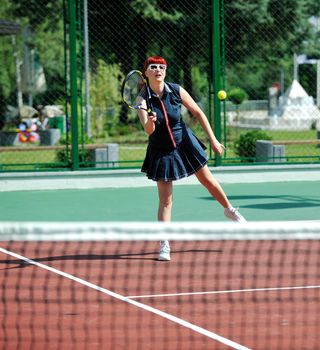 young fit woman play tennis outdoor on orange tennis field at early morning