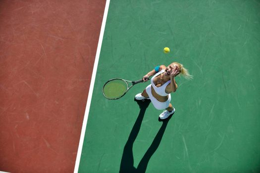 young fit woman play tennis outdoor on orange tennis field at early morning