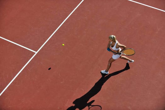 young fit woman play tennis outdoor on orange tennis field at early morning 