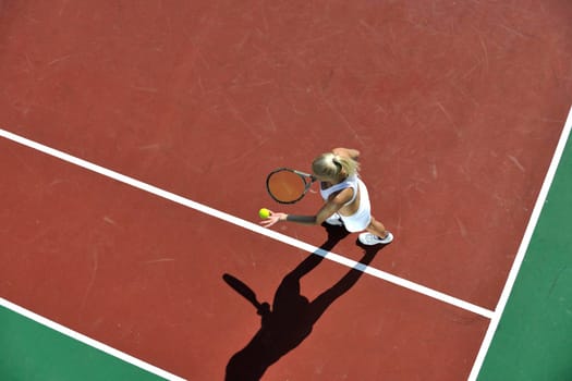 young fit woman play tennis outdoor on orange tennis field at early morning