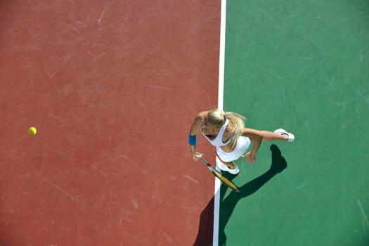 young fit woman play tennis outdoor on orange tennis field at early morning