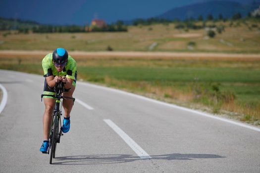 triathlon athlete riding professional racing bike at workout on curvy country road